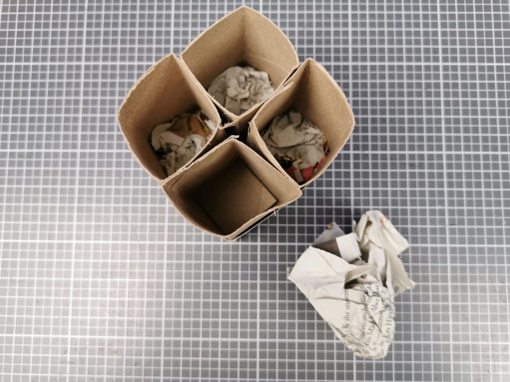 zerknüllte Zeitungspapierstücke einfüllen